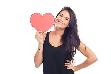 Image showing beautiful happy brunette woman holding and showing a big red hea