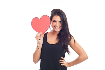 Image showing beautiful happy brunette woman holding and showing a big red hea