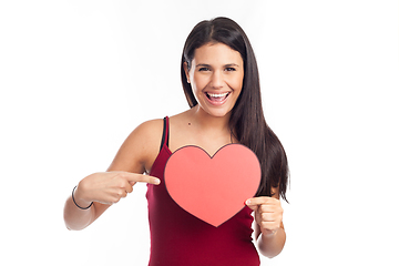 Image showing beautiful happy brunette woman holding and showing a big red hea