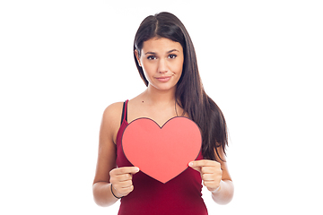 Image showing beautiful happy brunette woman holding and showing a big red hea