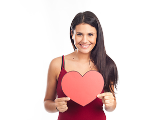 Image showing beautiful happy brunette woman holding and showing a big red hea