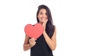 Image showing beautiful happy brunette woman holding and showing a big red hea