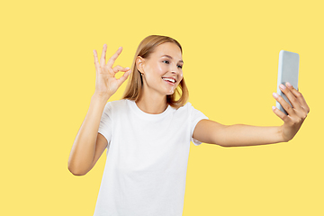 Image showing Caucasian young woman\'s half-length portrait on yellow background