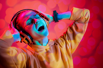 Image showing Young woman singing on multi-colored bokeh background