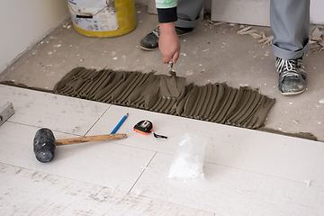 Image showing worker installing the ceramic wood effect tiles on the floor