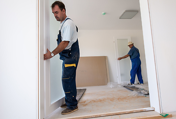 Image showing carpenters installing glass door with a wooden frame