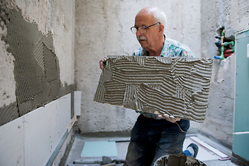 Image showing worker installing big ceramic tiles