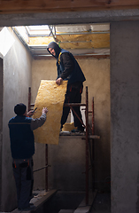 Image showing roofer man installing thermal insulation layer