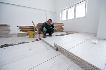 Image showing worker installing the ceramic wood effect tiles on the floor