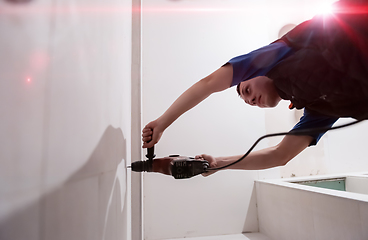 Image showing construction worker drilling holes in the bathroom