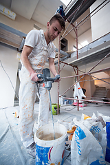 Image showing construction worker mixing plaster in bucket