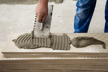 Image showing worker installing the ceramic wood effect tiles on the floor