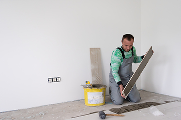 Image showing worker installing the ceramic wood effect tiles on the floor