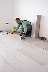 Image showing worker installing the ceramic wood effect tiles on the floor