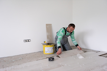 Image showing worker installing the ceramic wood effect tiles on the floor