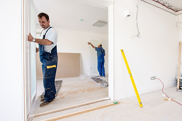 Image showing carpenters installing glass door with a wooden frame