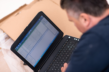 Image showing man using laptop while lying on cardboard box