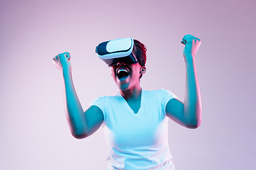 Image showing Young african-american woman\'s using VR-glasses in neon light