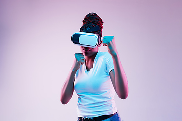 Image showing Young african-american woman\'s using VR-glasses in neon light