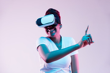 Image showing Young african-american woman\'s using VR-glasses in neon light