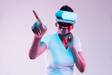 Image showing Young african-american woman\'s using VR-glasses in neon light