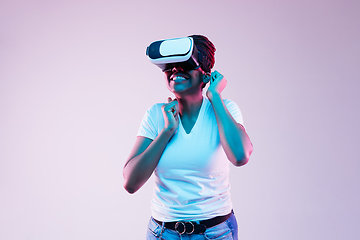 Image showing Young african-american woman\'s using VR-glasses in neon light