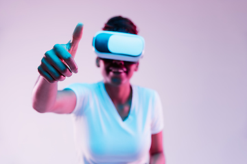 Image showing Young african-american woman\'s using VR-glasses in neon light