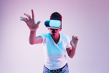 Image showing Young african-american woman\'s using VR-glasses in neon light