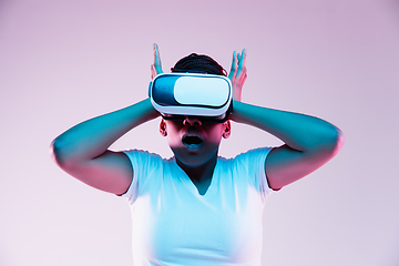 Image showing Young african-american woman\'s using VR-glasses in neon light