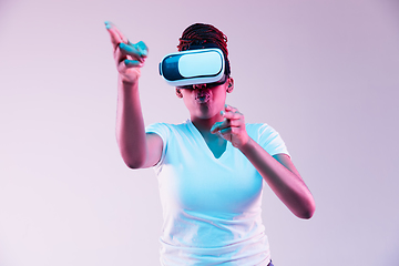 Image showing Young african-american woman\'s using VR-glasses in neon light