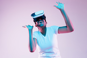 Image showing Young african-american woman\'s using VR-glasses in neon light