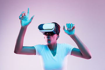 Image showing Young african-american woman\'s using VR-glasses in neon light