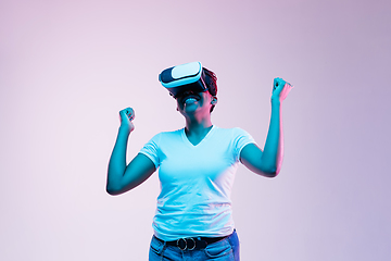 Image showing Young african-american woman\'s using VR-glasses in neon light