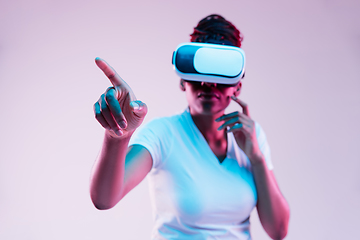 Image showing Young african-american woman\'s using VR-glasses in neon light