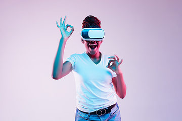 Image showing Young african-american woman\'s using VR-glasses in neon light