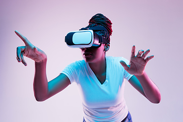 Image showing Young african-american woman\'s using VR-glasses in neon light