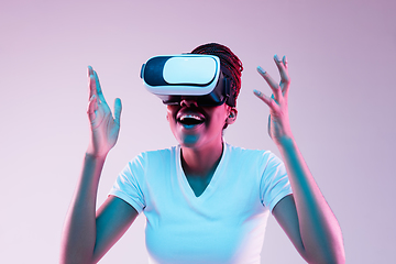 Image showing Young african-american woman\'s using VR-glasses in neon light