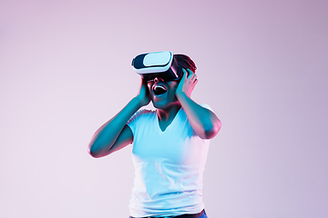 Image showing Young african-american woman\'s using VR-glasses in neon light