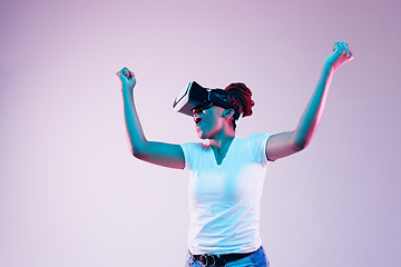 Image showing Young african-american woman\'s using VR-glasses in neon light