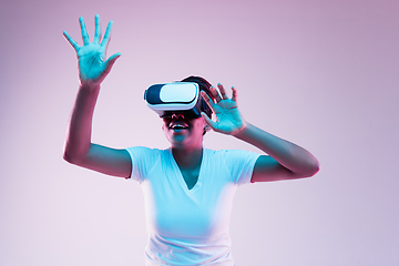 Image showing Young african-american woman\'s using VR-glasses in neon light