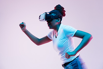 Image showing Young african-american woman\'s using VR-glasses in neon light