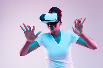 Image showing Young african-american woman\'s using VR-glasses in neon light