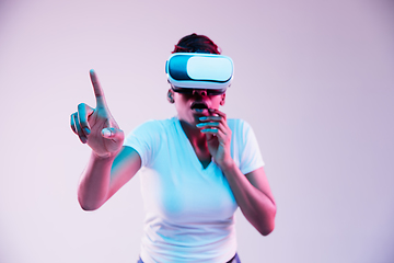 Image showing Young african-american woman\'s using VR-glasses in neon light