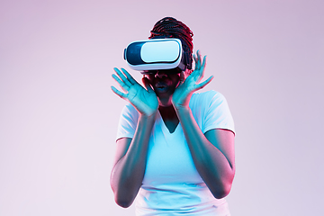 Image showing Young african-american woman\'s using VR-glasses in neon light