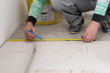 Image showing worker installing the ceramic wood effect tiles on the floor