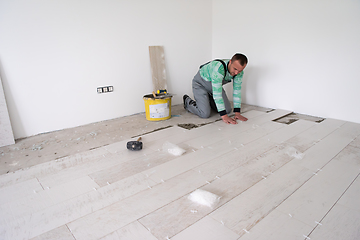 Image showing worker installing the ceramic wood effect tiles on the floor