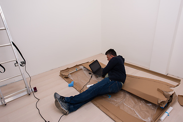 Image showing man using laptop while lying on cardboard box