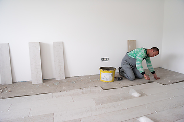 Image showing worker installing the ceramic wood effect tiles on the floor