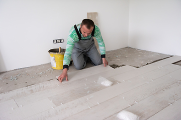 Image showing worker installing the ceramic wood effect tiles on the floor