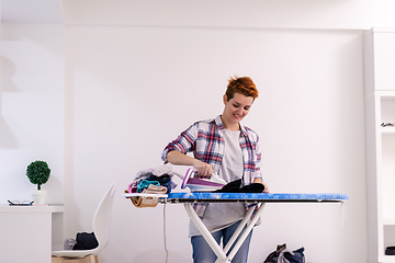 Image showing Red haired woman ironing clothes at home